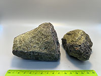 two green crystaline rocks with a black surface coating of basaltic lava